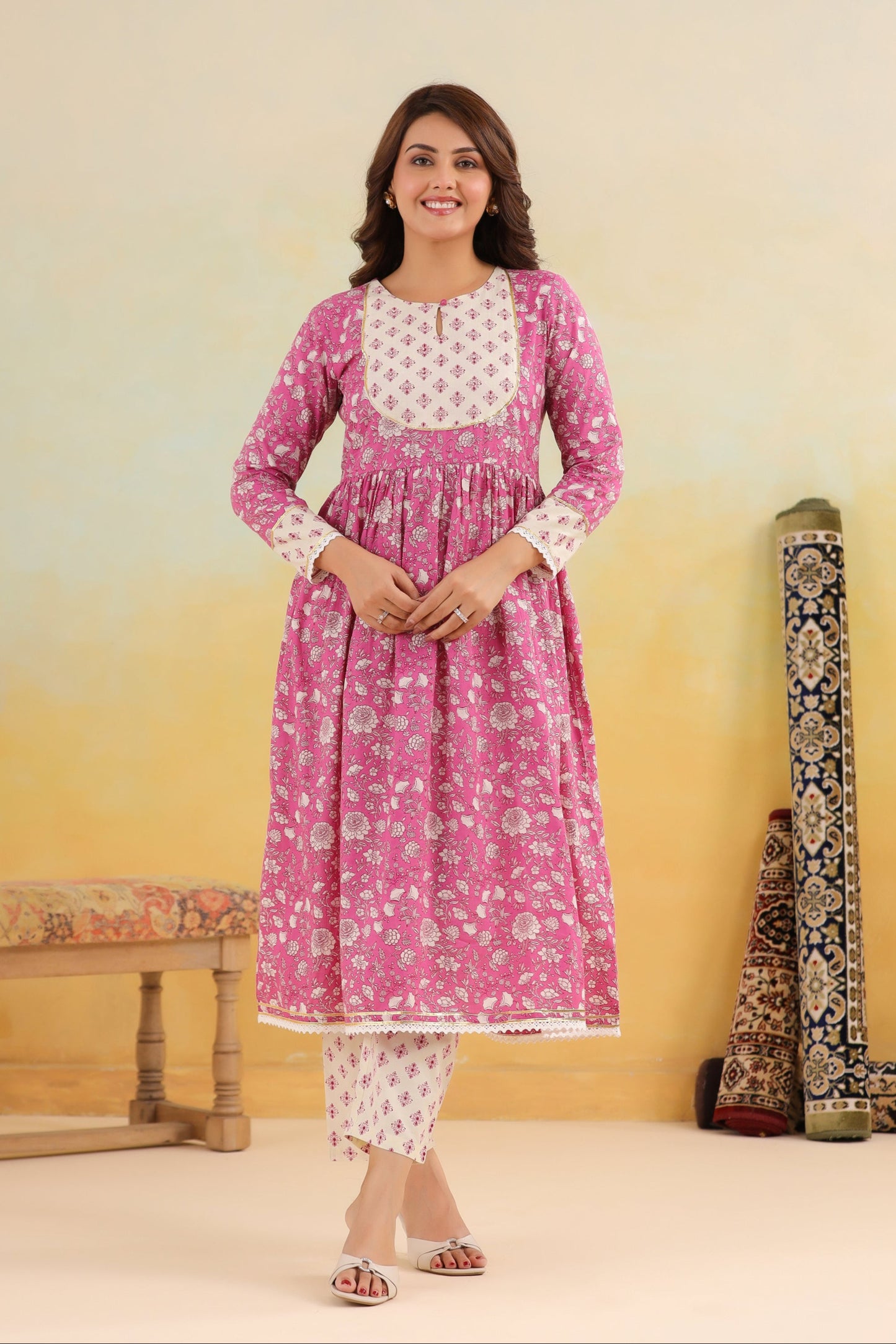 Woman wearing a pink floral kurta with white patterns in a minimalistic setting.
