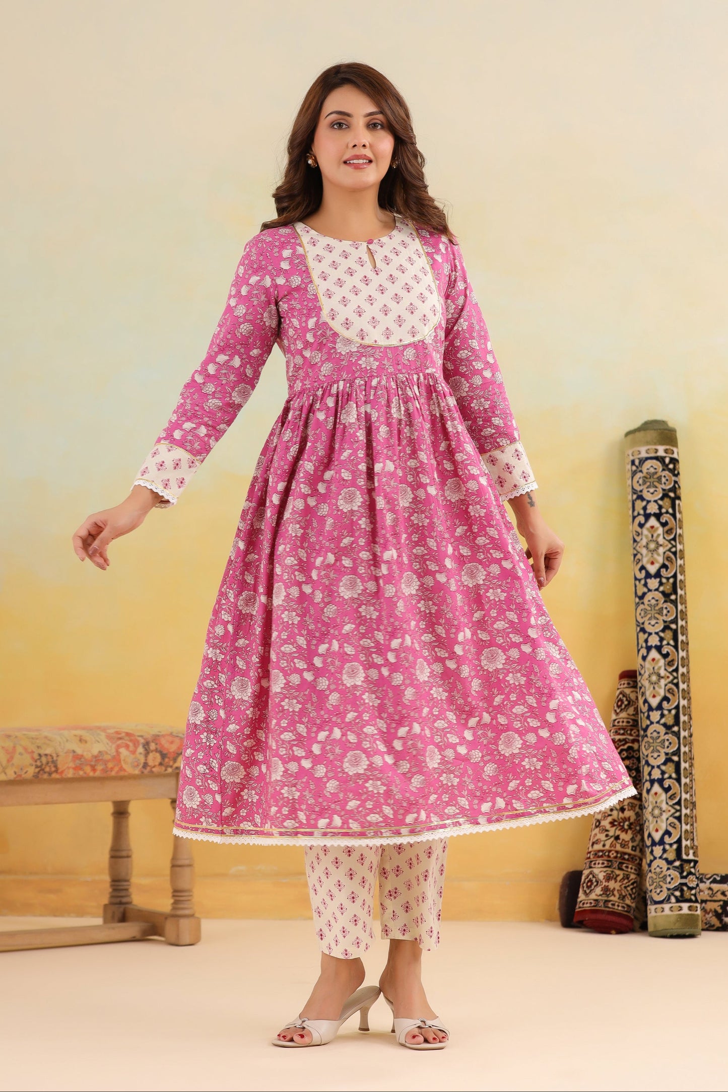 Woman wearing a pink floral dress with a white top against a yellow background