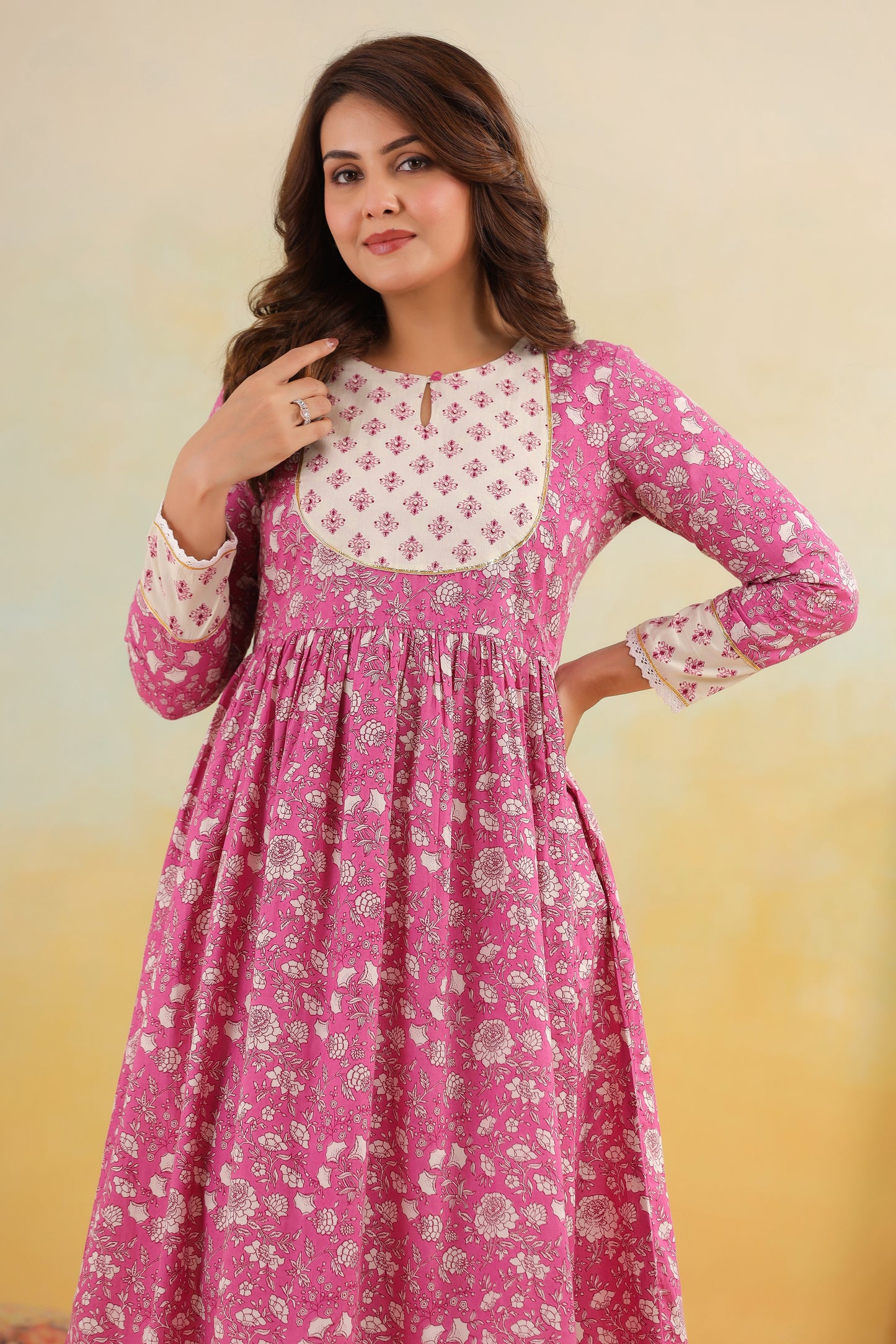 Woman wearing a pink and white floral dress against a yellow background