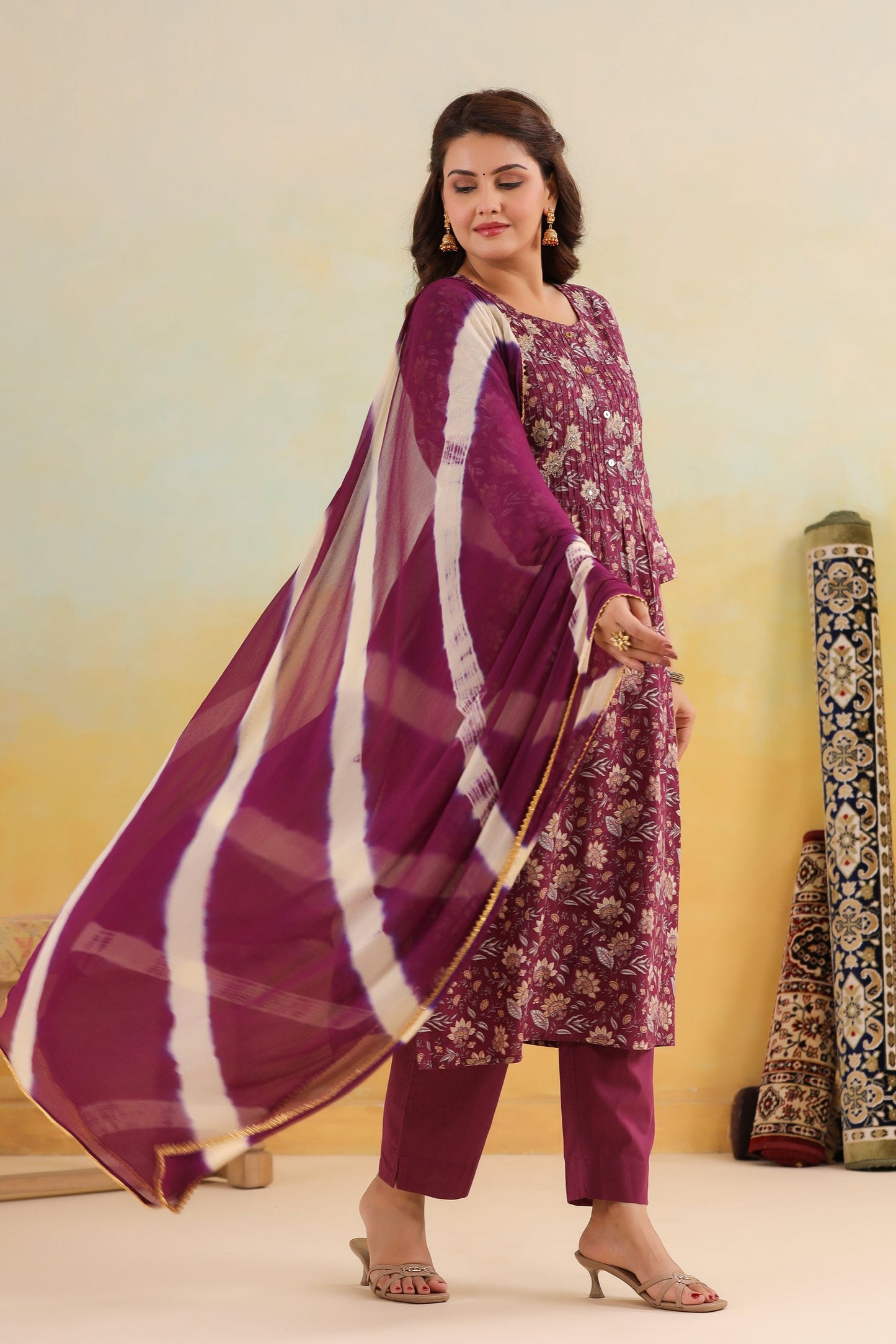 Woman in a purple traditional outfit with a matching dupatta against a yellow background