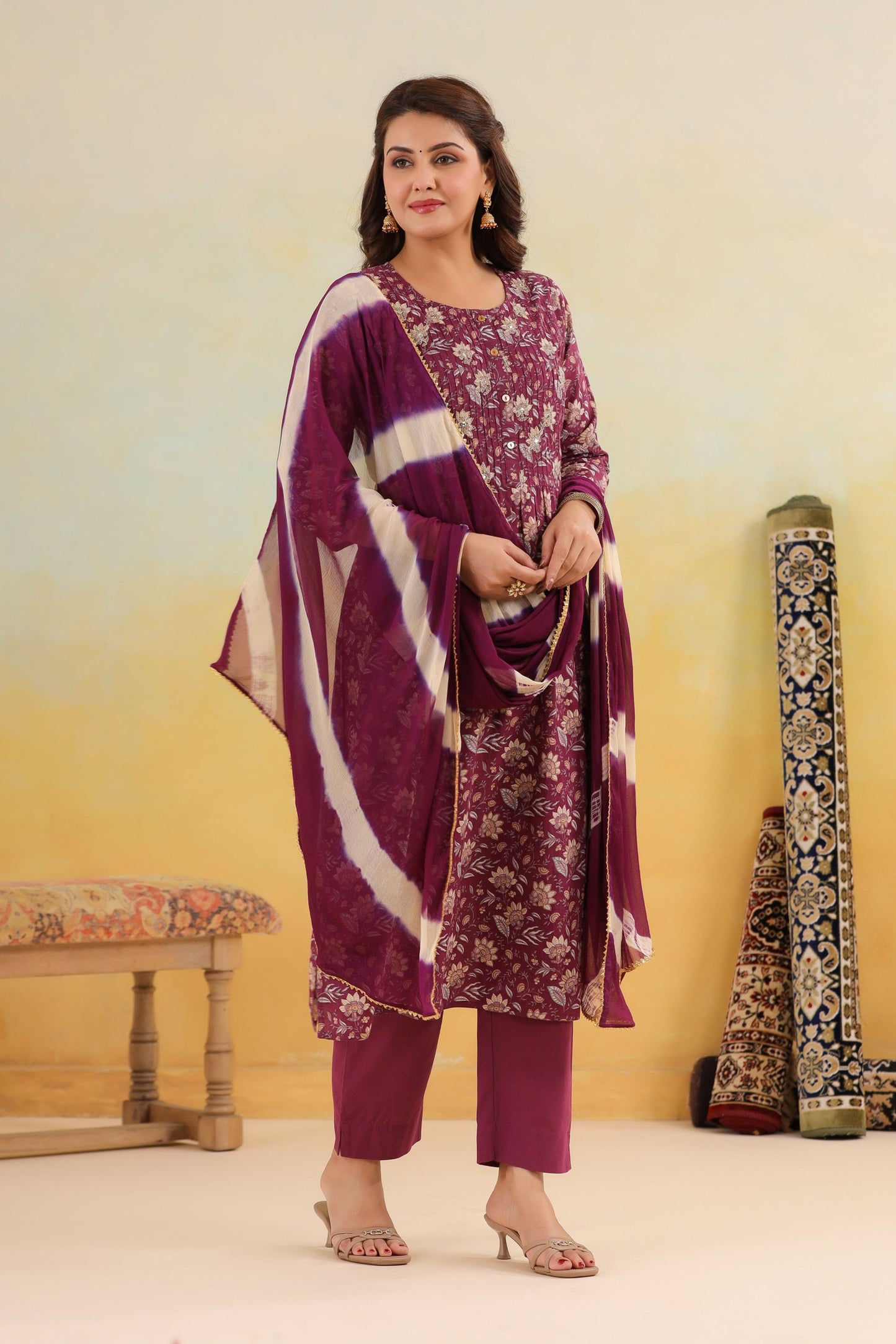 Woman wearing a purple floral outfit with a matching dupatta against a yellow background