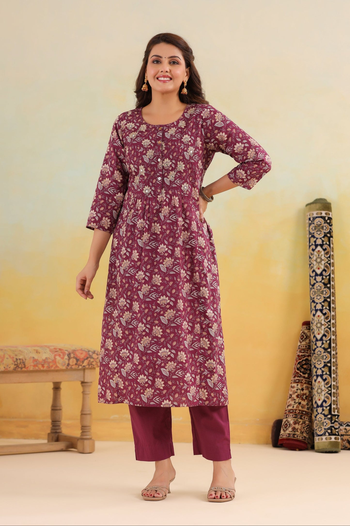 Woman wearing a purple floral kurta with pants against a yellow background