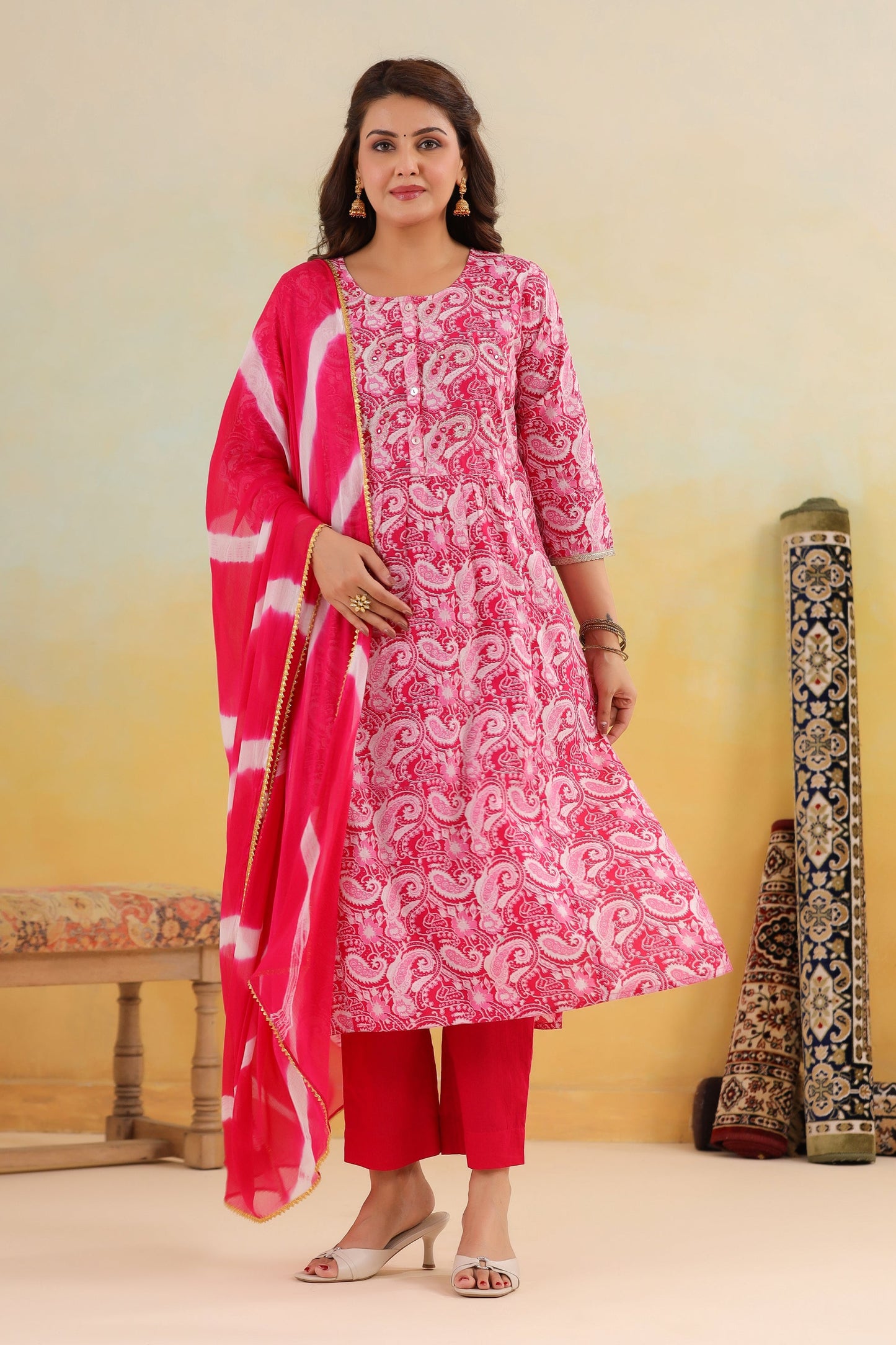 Woman wearing a pink traditional outfit with a white pattern against a yellow background