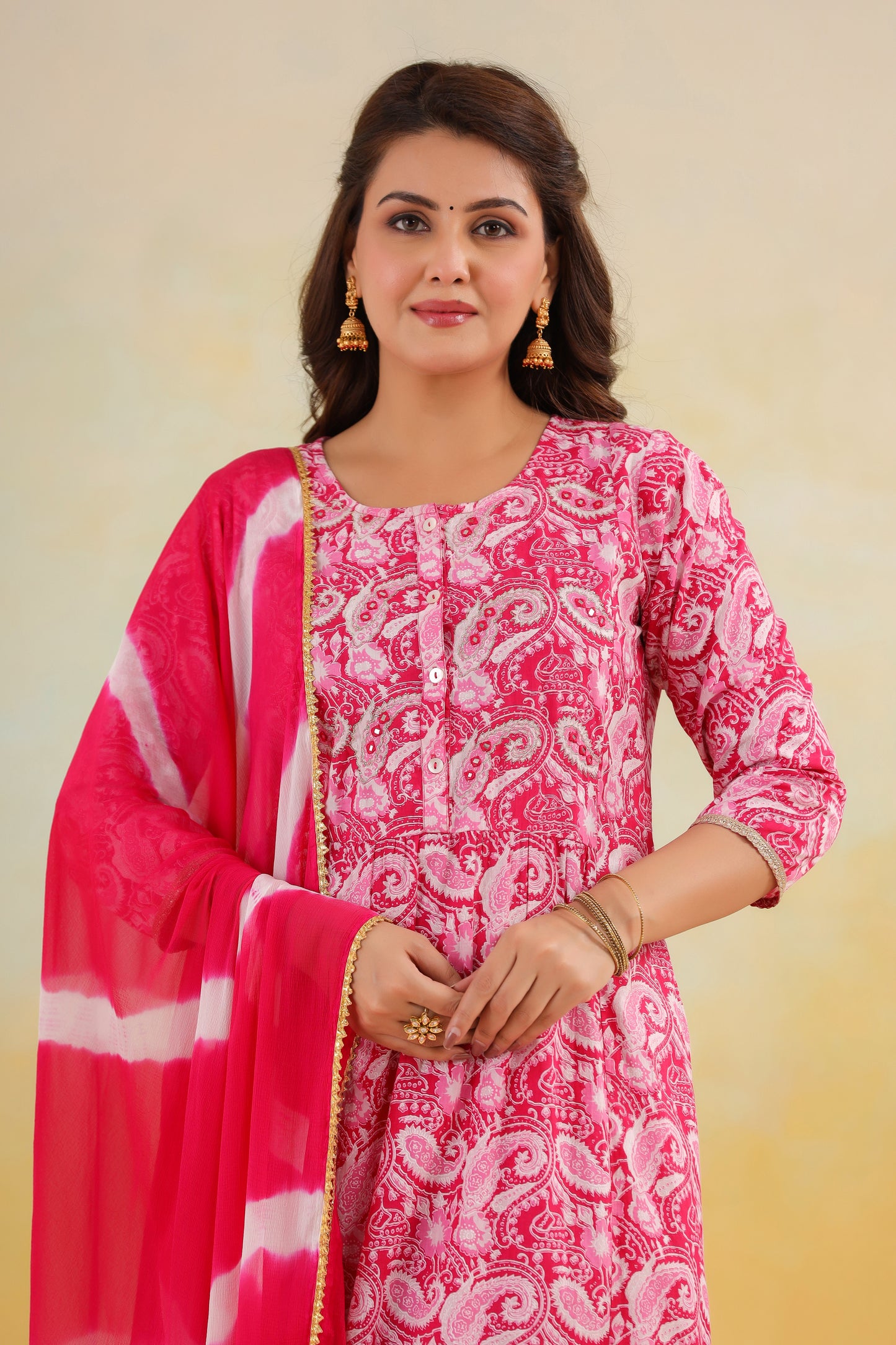 Woman wearing a pink and white patterned kurta with a matching dupatta on a beige background