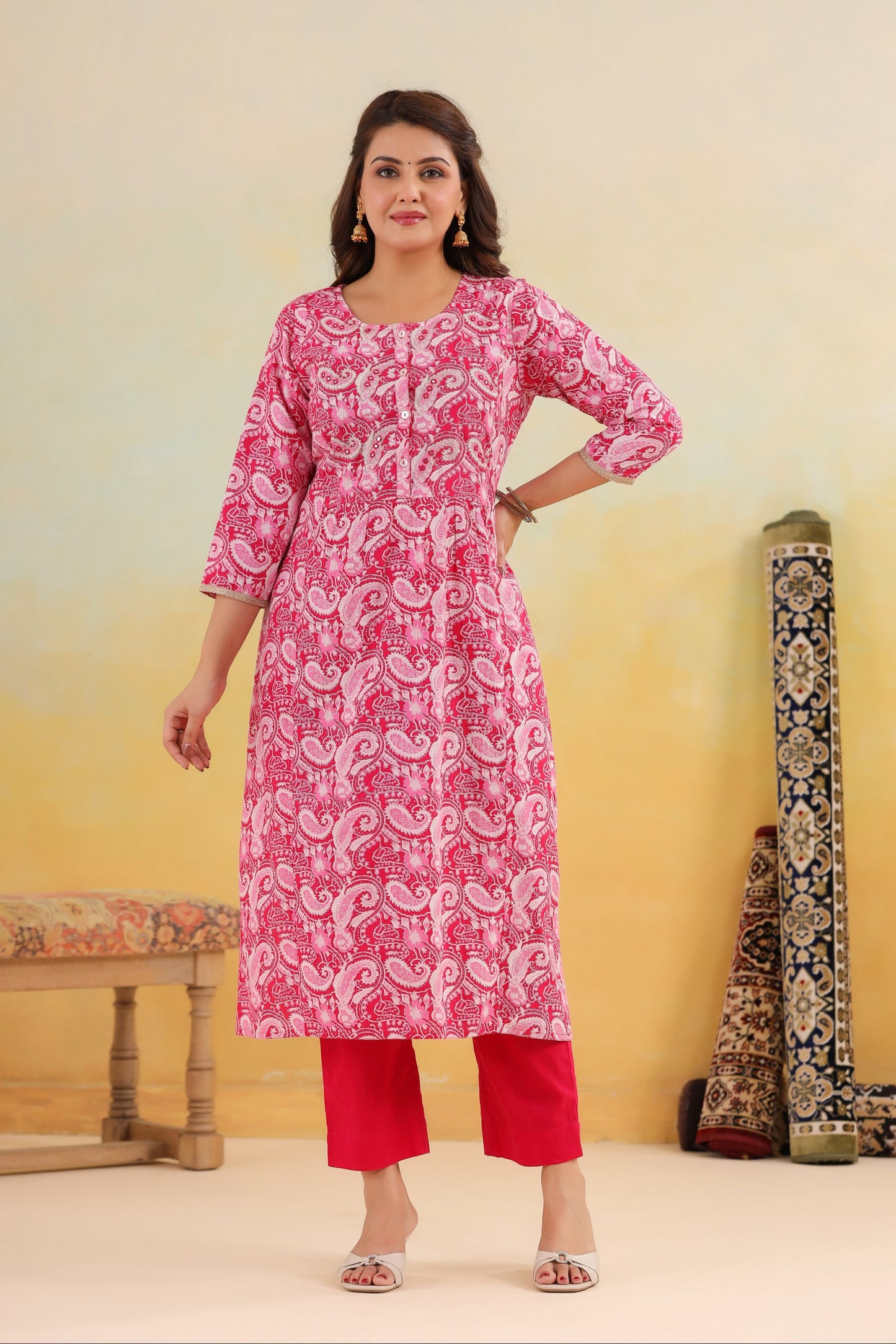 Woman wearing a pink kurta with white patterns against a yellow background