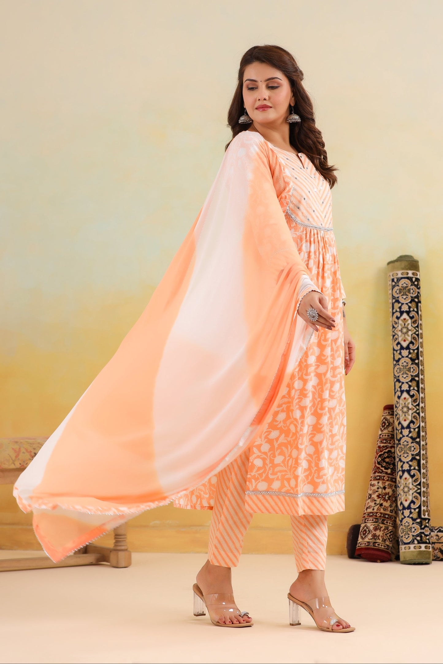 Woman in peach and white traditional outfit with a plain background