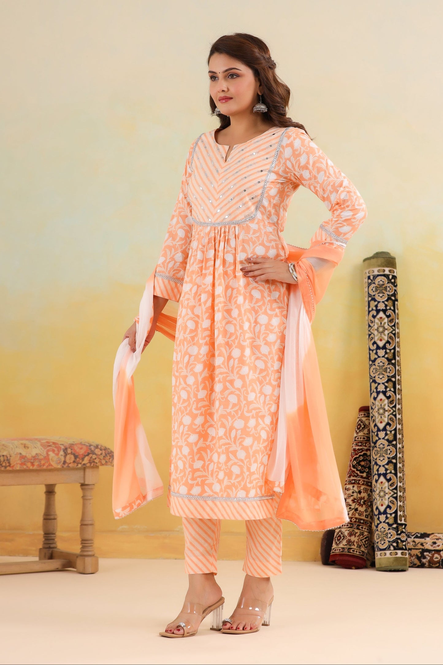 Woman wearing a peach-colored traditional outfit with a yellow gradient background