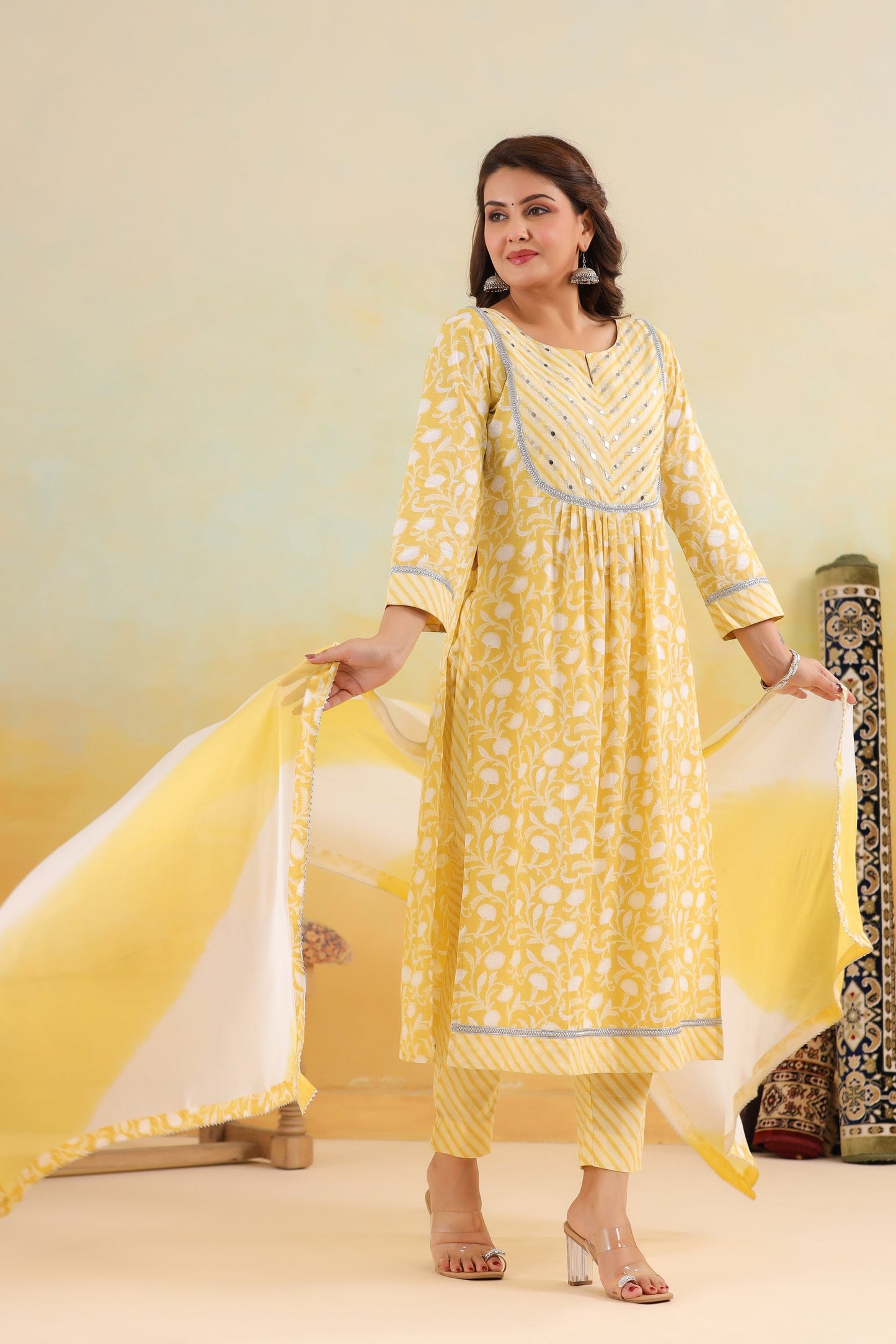 Woman wearing a yellow traditional outfit with a white dupatta against a light yellow background