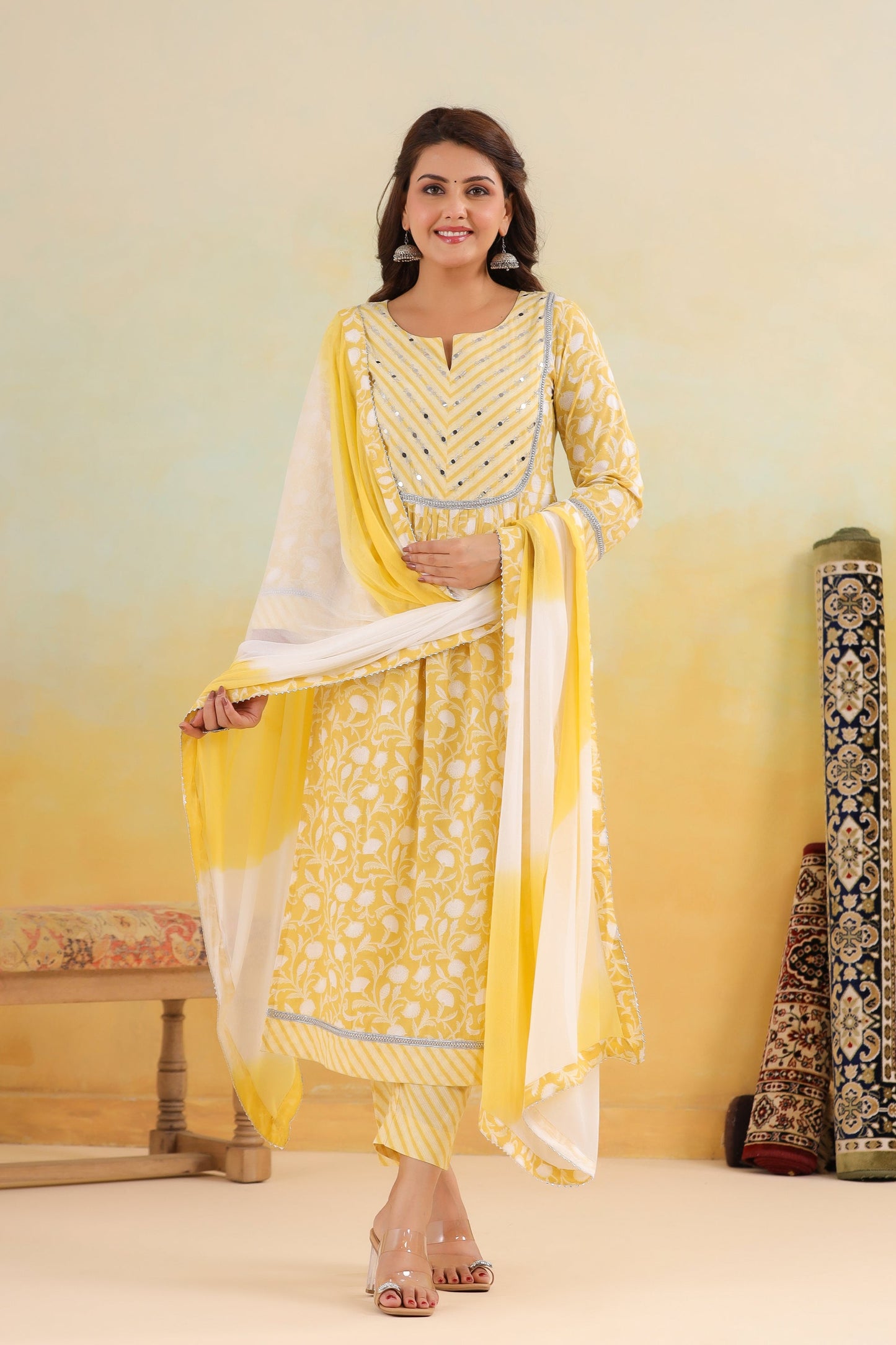 Woman in a yellow and white traditional outfit with a decorative background
