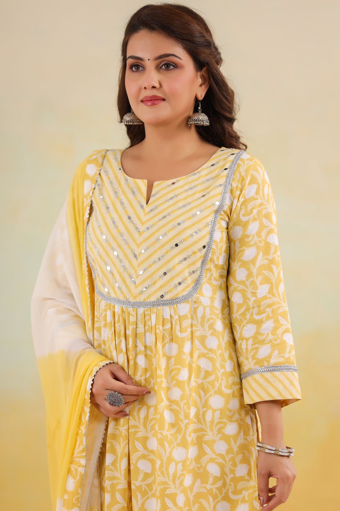 Woman wearing a yellow and white traditional outfit with a plain background