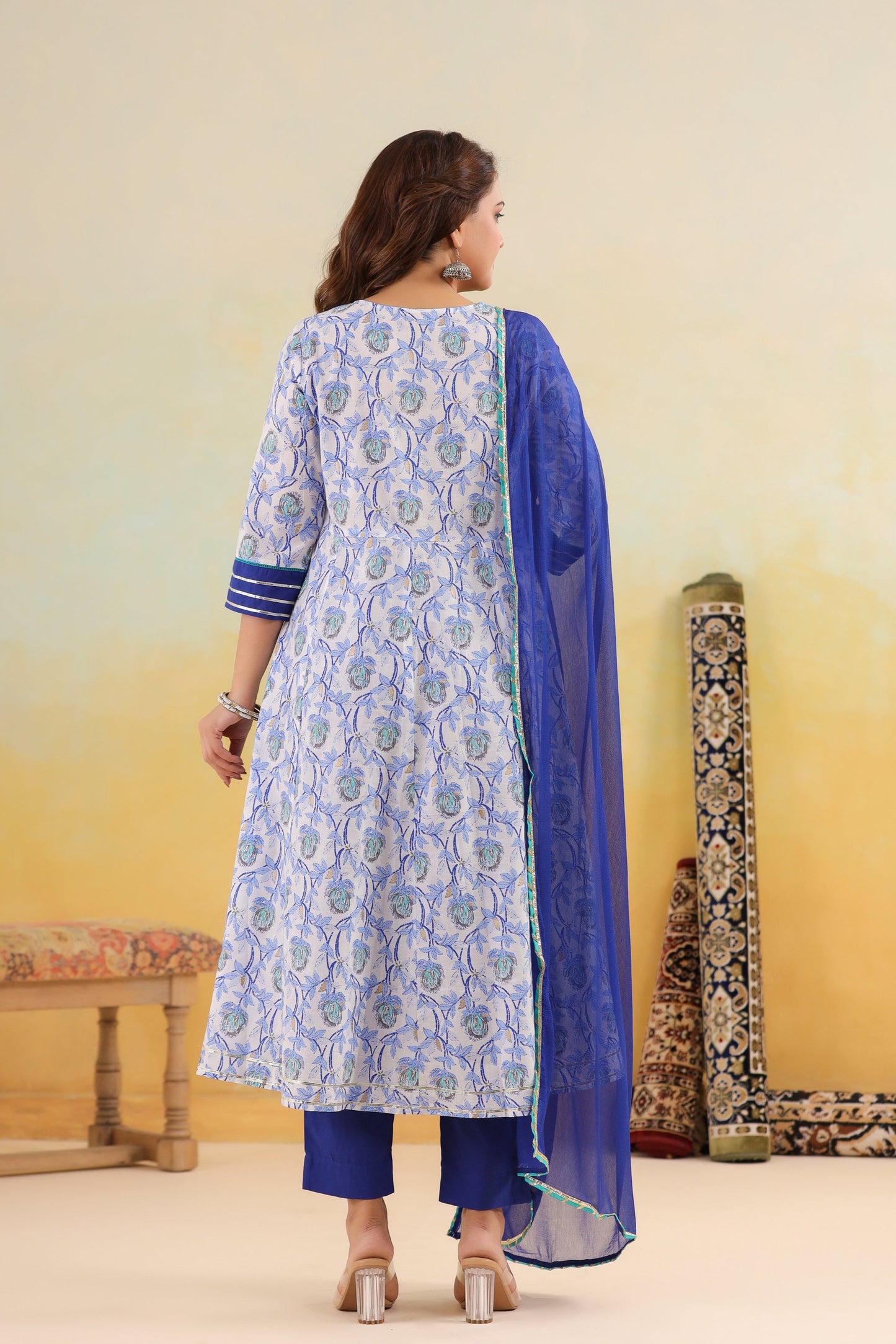 Woman wearing a blue and white patterned kurta with a blue dupatta against a yellow background