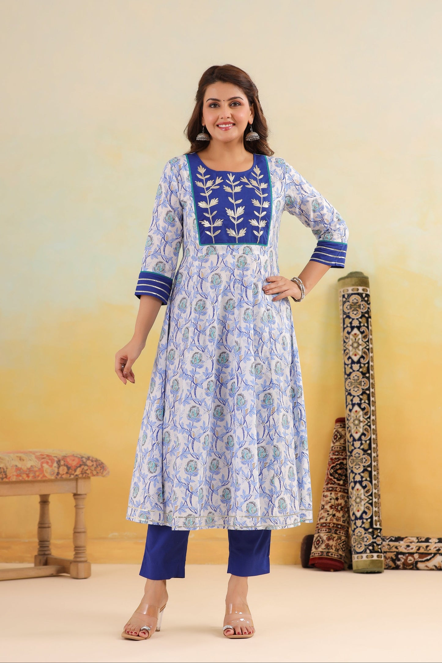 Woman wearing a blue and white patterned kurta with blue pants against a yellow background