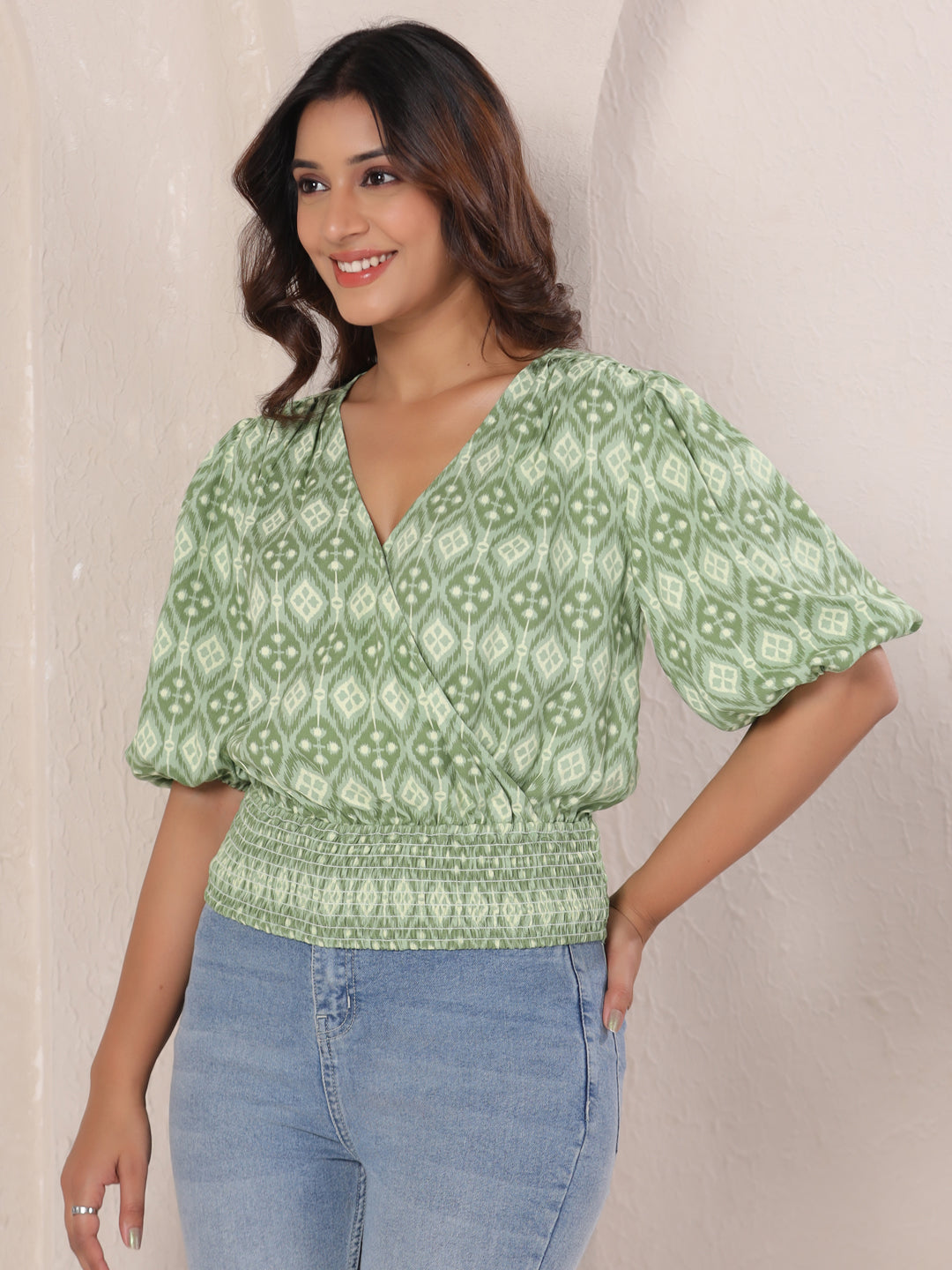 Green printed cotton top with puff sleeves and smocked waist, paired with jeans for casual wear