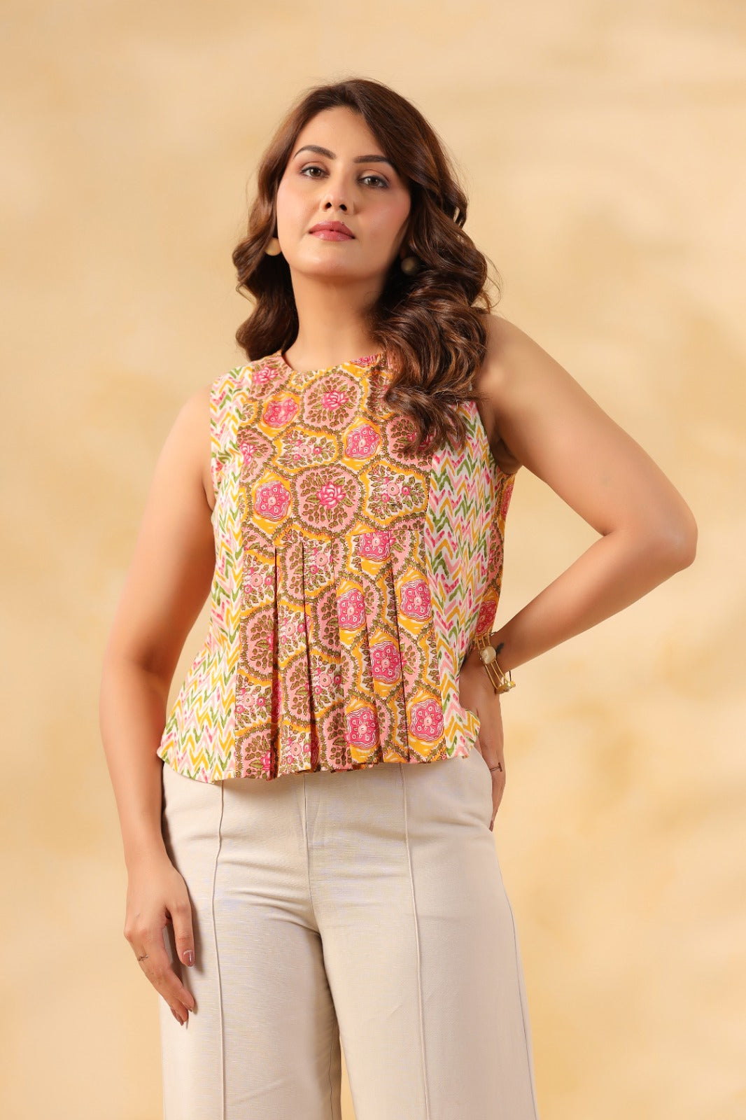 Women's sleeveless printed top with peplum hem, paired with white pants for casual or office wear