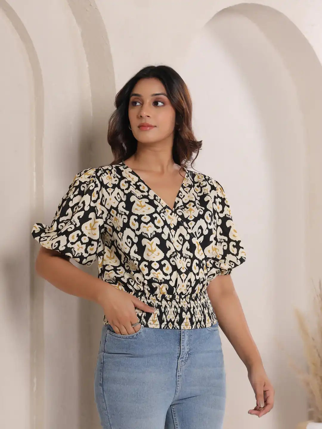 Woman wearing black and cream printed cotton top with puff sleeves, paired with blue jeans