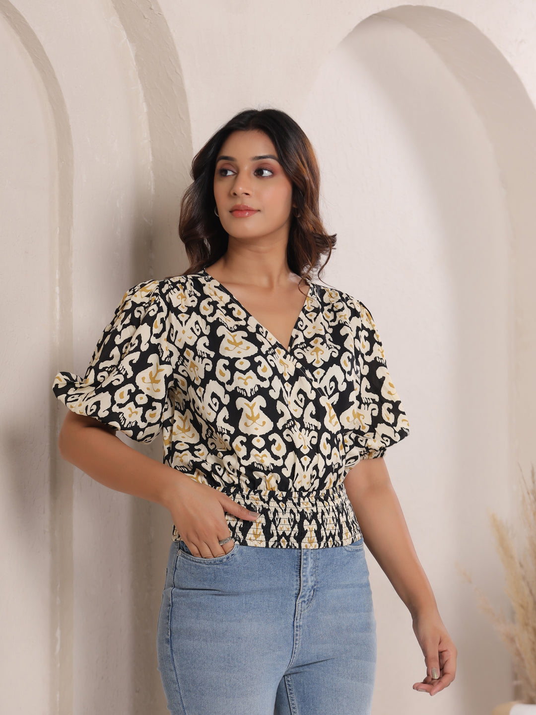 Woman wearing black and cream printed cotton top with puff sleeves, paired with blue jeans