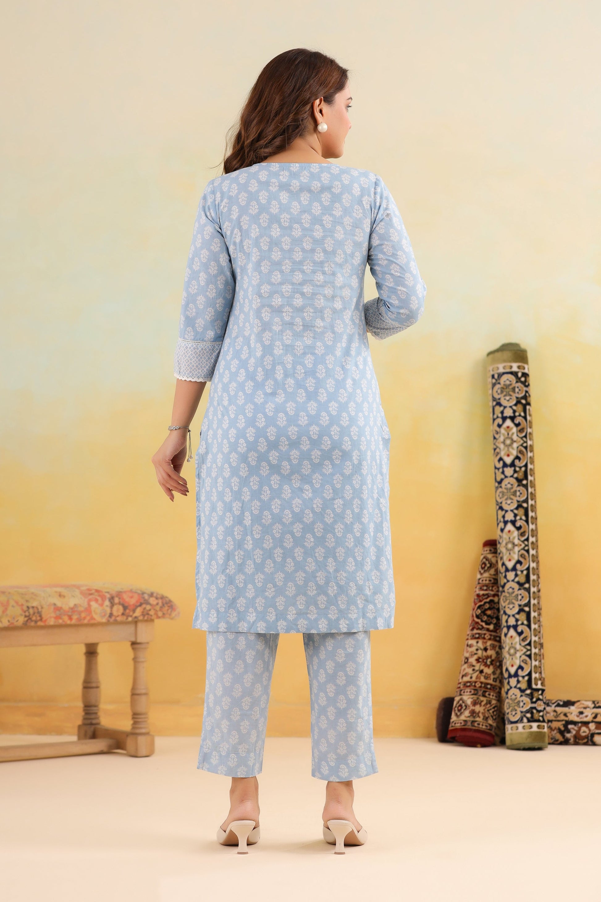 Woman wearing a light blue patterned outfit with a yellow and white gradient background.