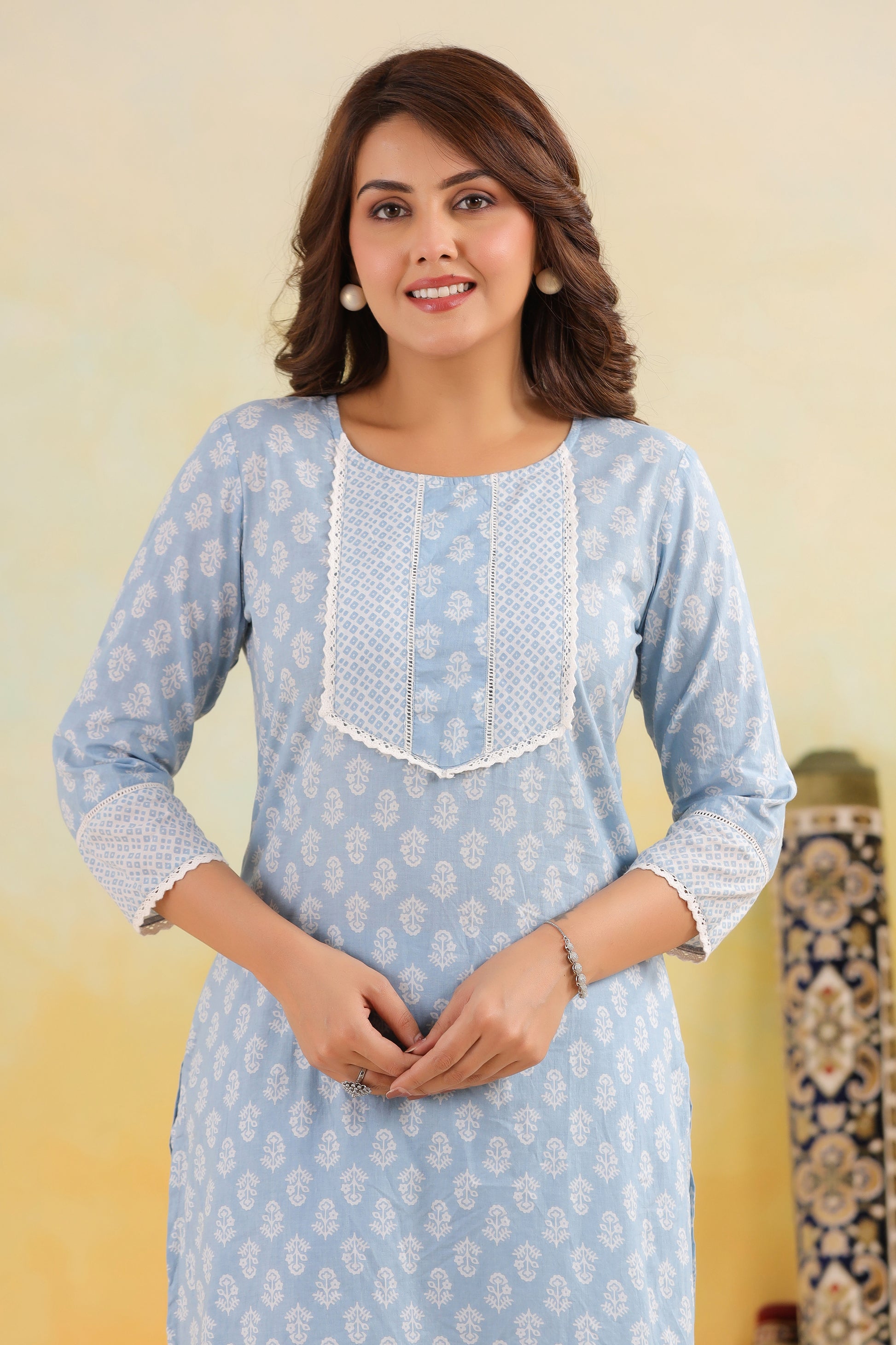 Woman wearing a light blue kurta with white floral patterns on a yellow background