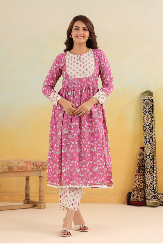 Woman wearing a pink floral kurta with white patterns in a minimalistic setting.