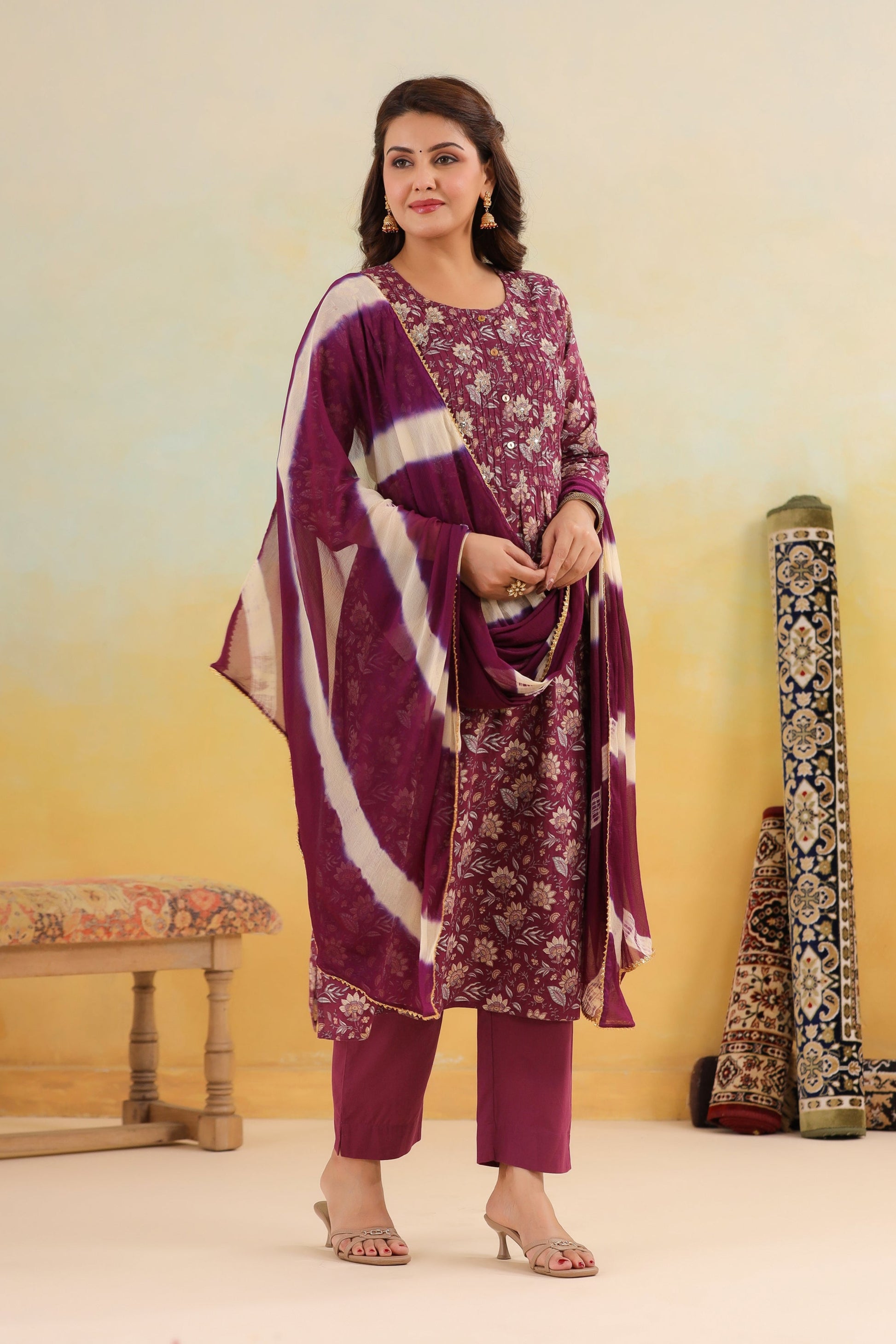 Woman wearing a purple floral outfit with a matching dupatta against a yellow background