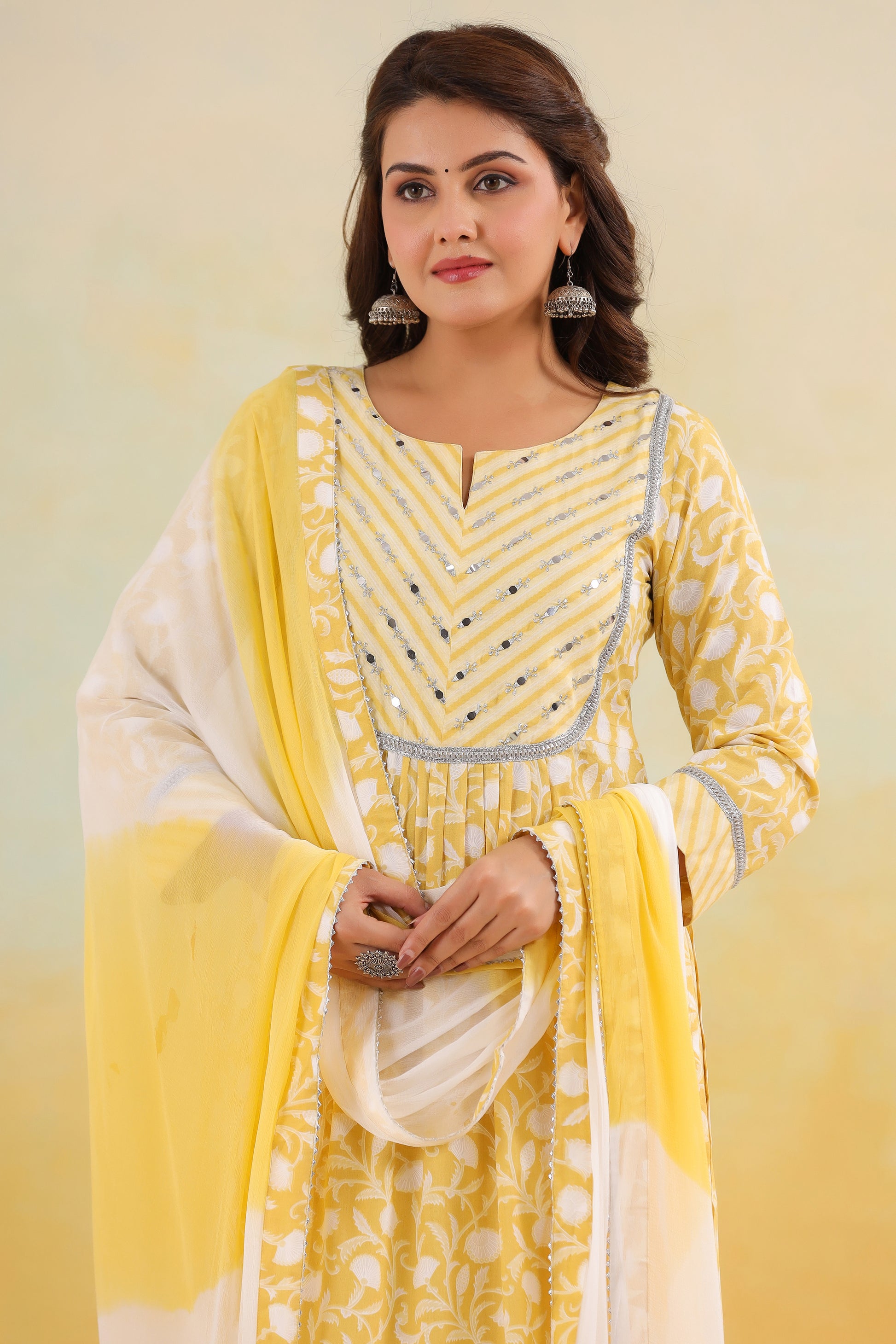 Woman wearing a yellow and white traditional outfit with a matching dupatta against a light background