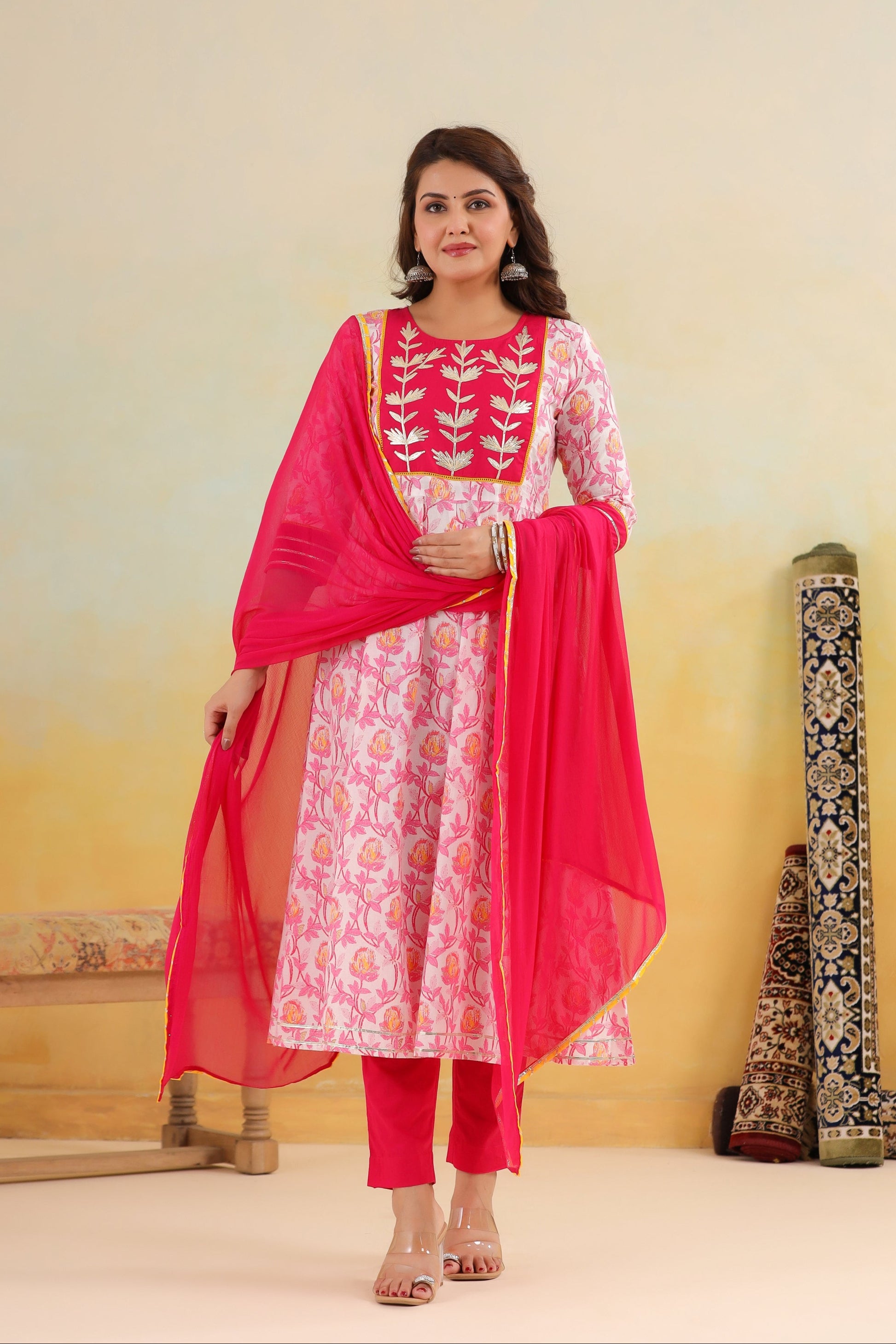 Woman wearing a pink and white traditional outfit with a dupatta against a yellow background