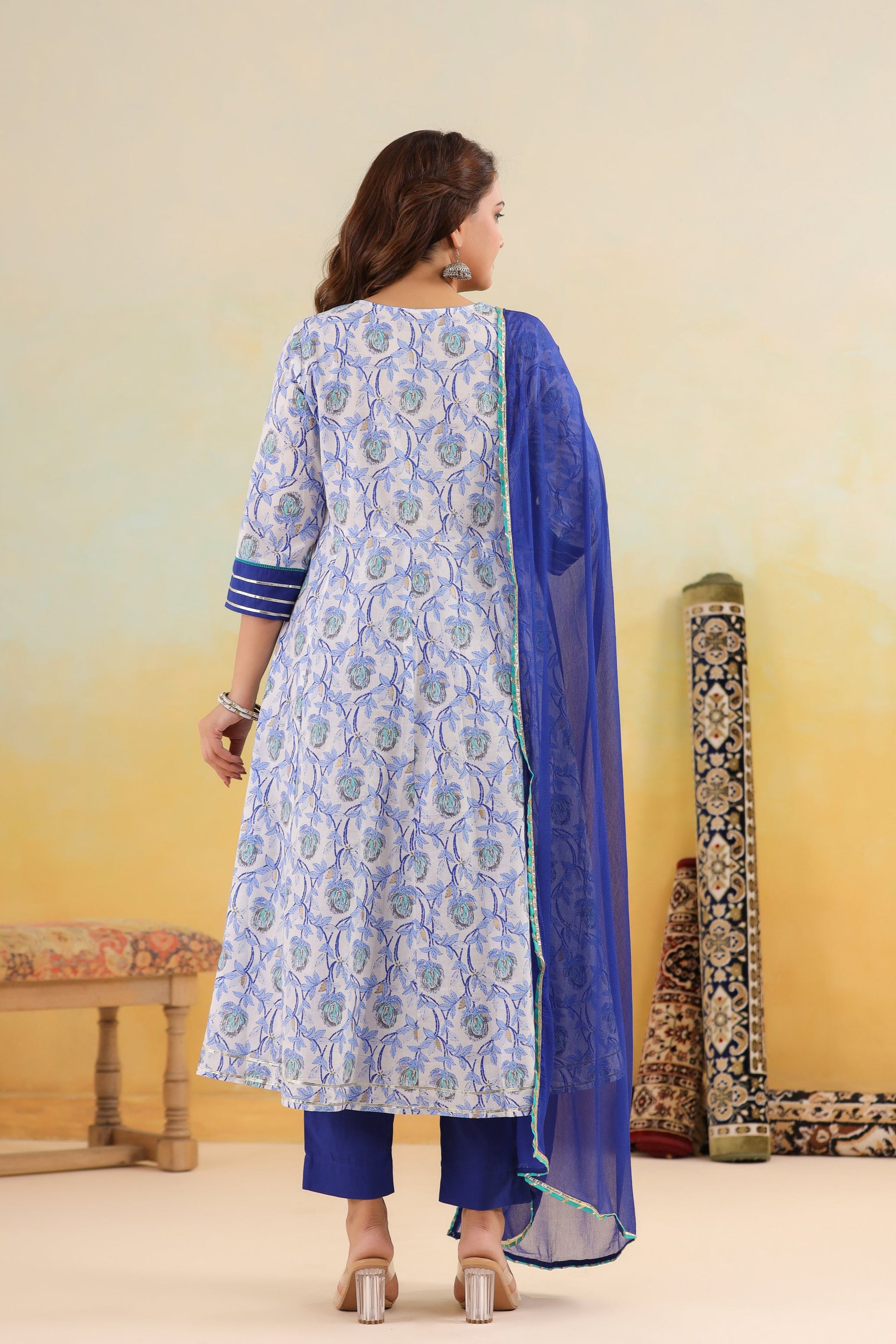 Woman wearing a blue and white patterned kurta with a blue dupatta against a yellow background