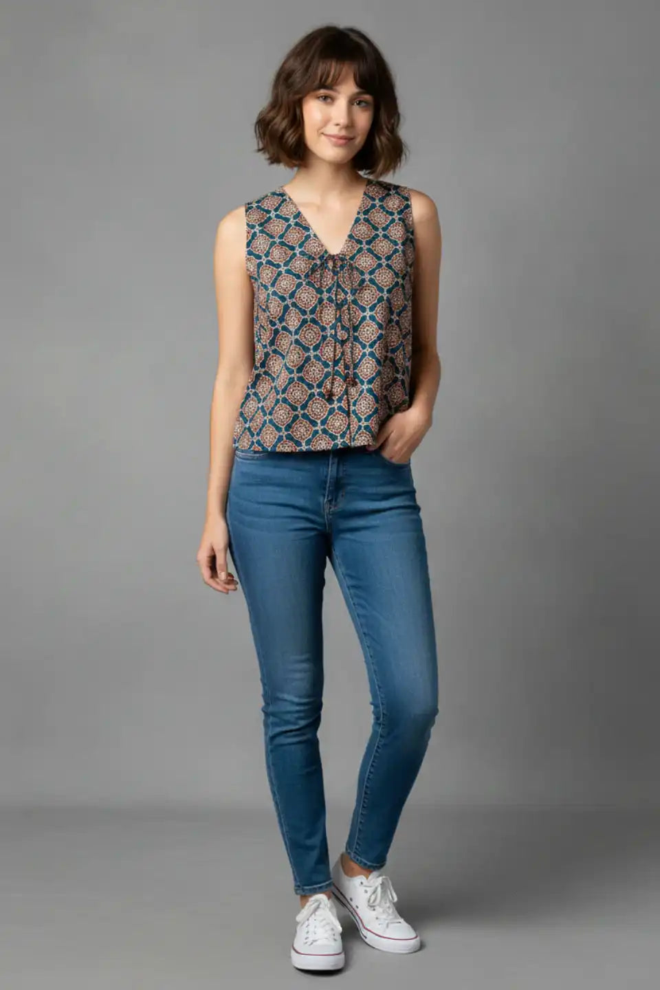 Woman wearing sleeveless printed top with V-neck and blue jeans, casual daily wear outfit