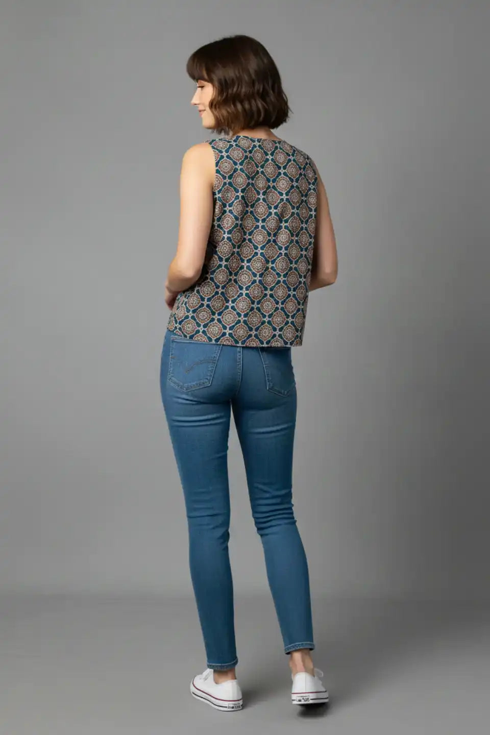 Woman wearing sleeveless printed cotton top with blue jeans, back view