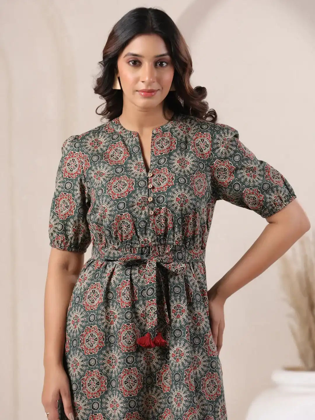 Woman in green printed cotton kurta with red tassels, puff sleeves, and tie waist for daily or office wear