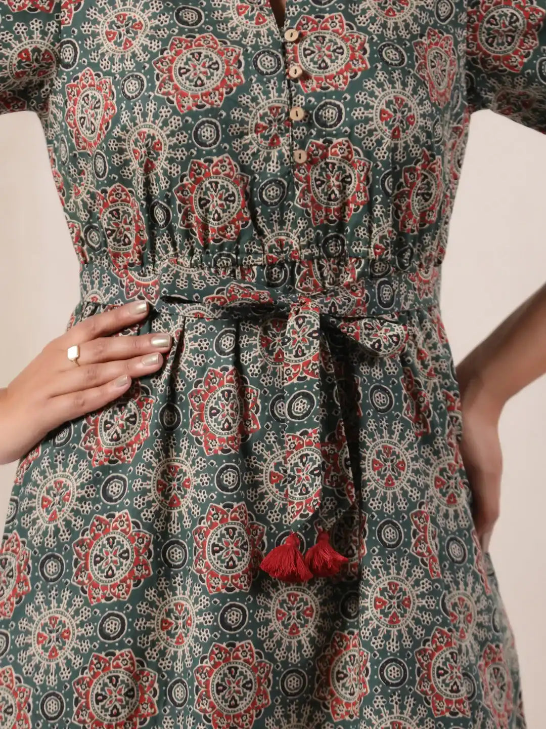 Green printed cotton kurta with red tassels, button front, and tie waist for women's daily or festive wear