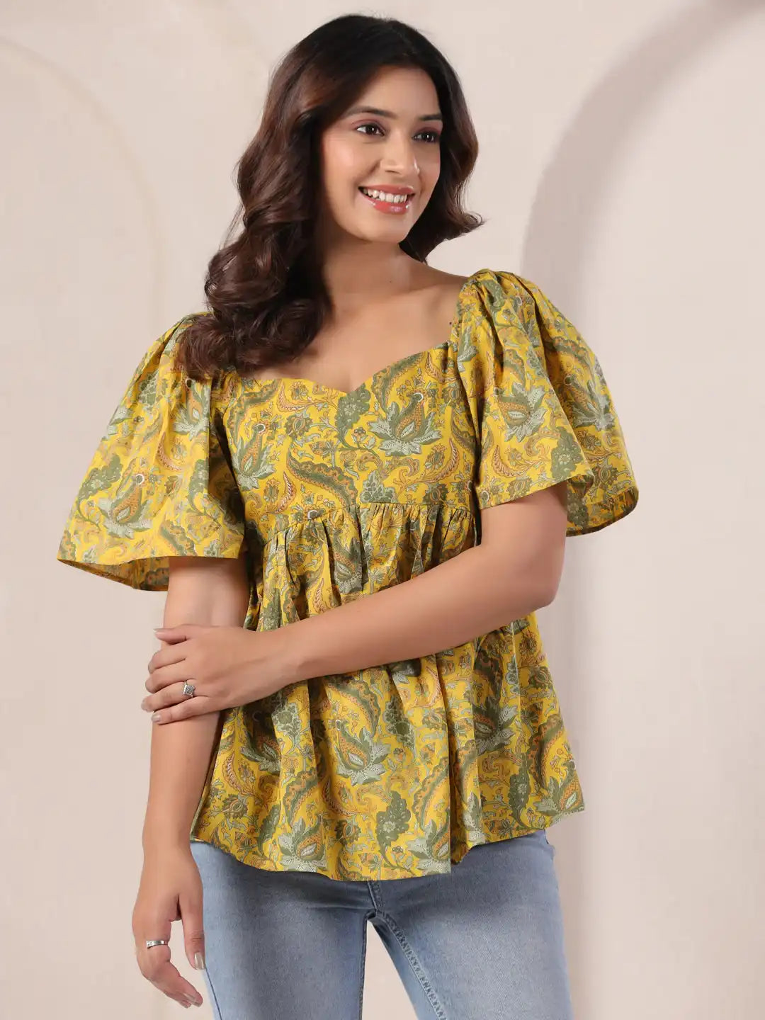 Yellow paisley print peplum top with puff sleeves for women, paired with jeans