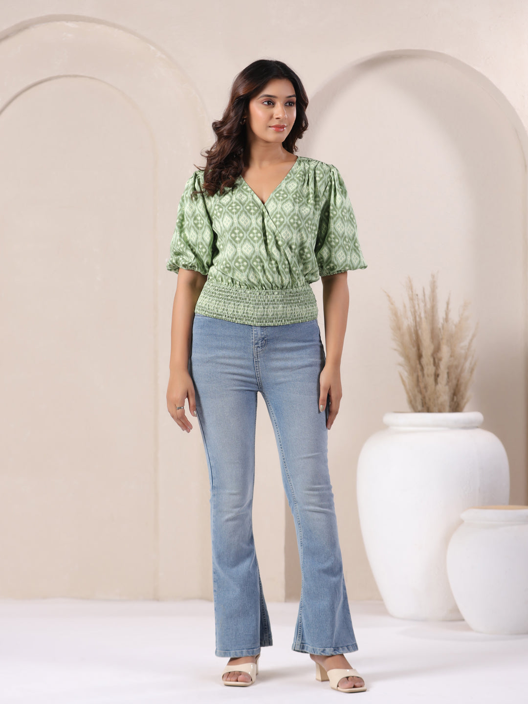 Green printed V-neck top with puff sleeves paired with flared jeans for women's casual wear