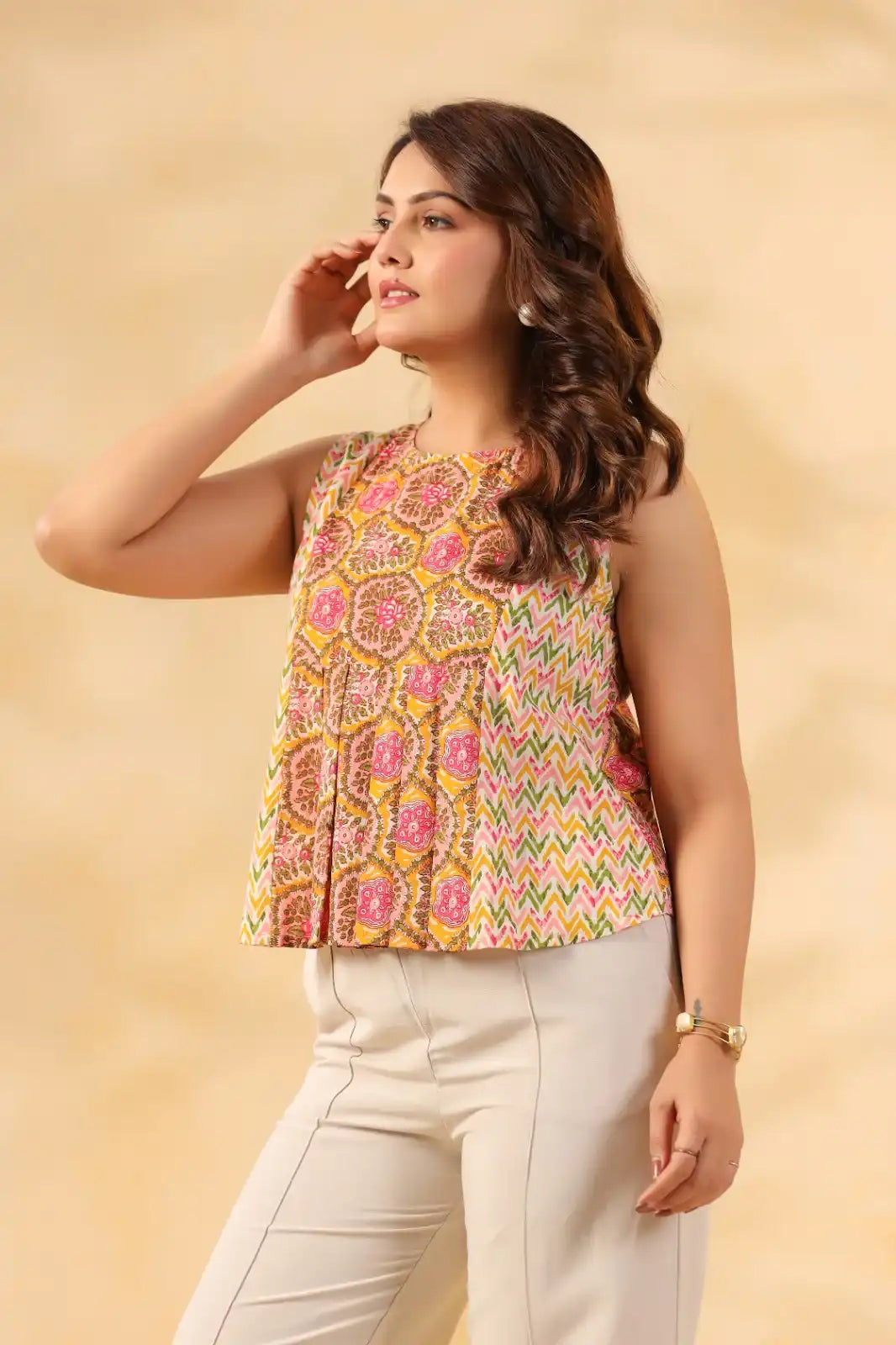 Colorful printed sleeveless top with floral and chevron patterns, paired with white pants for casual wear