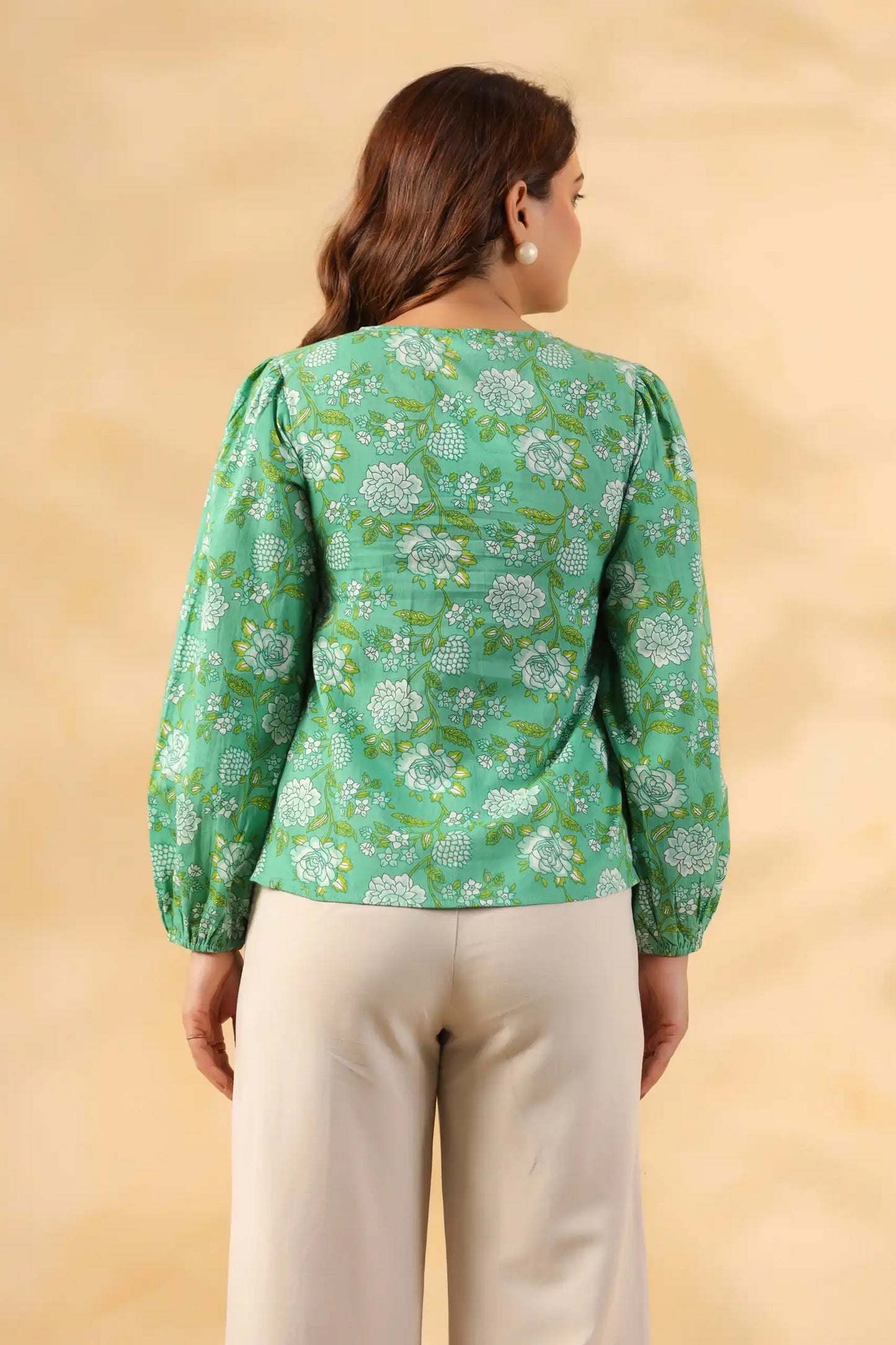 Green floral print cotton kurta with puff sleeves, back view, paired with cream pants for women