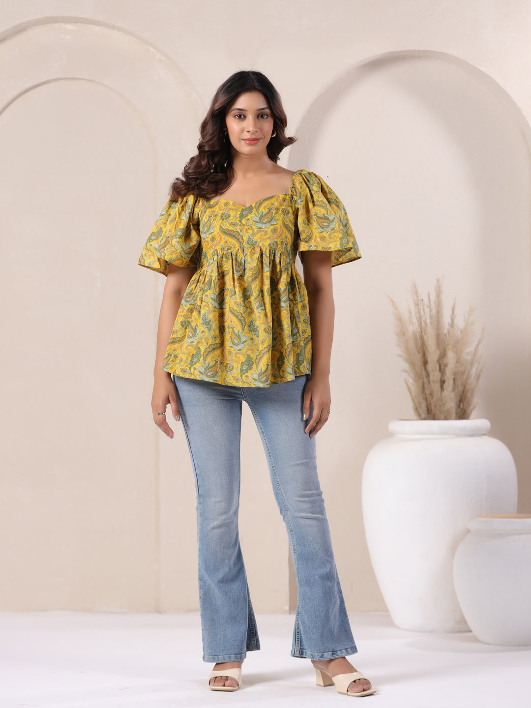 Yellow paisley print peplum top with puff sleeves, paired with blue flared jeans for casual wear