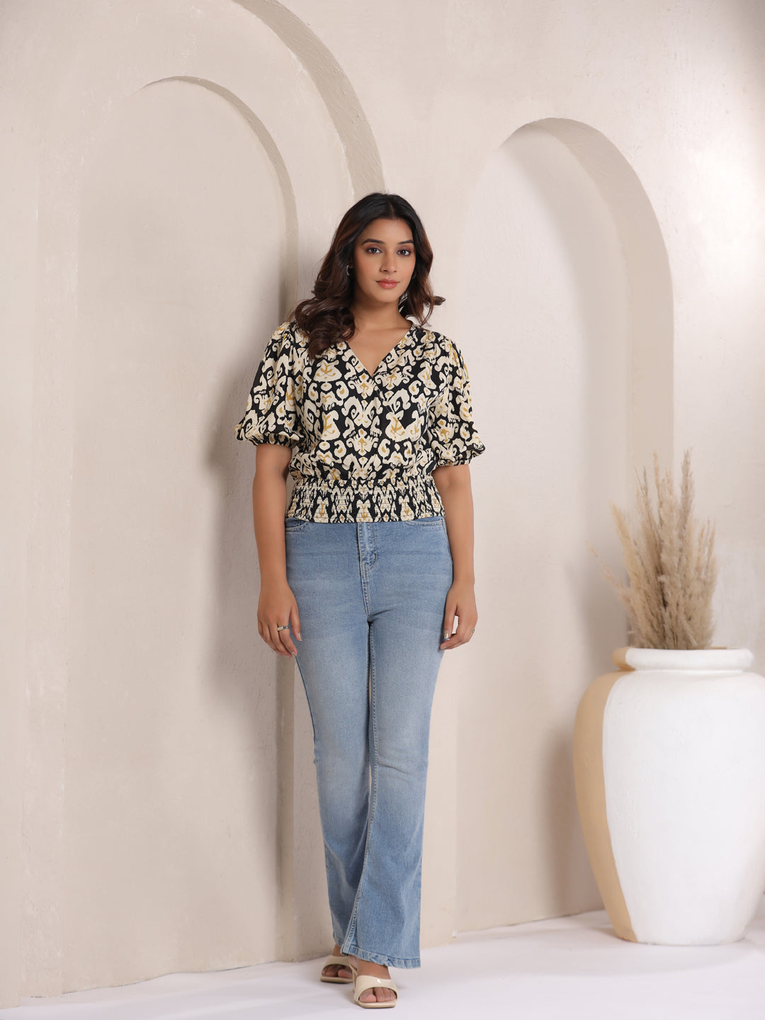 Woman wearing black and cream floral print top with puff sleeves and light blue jeans, stylish casual outfit